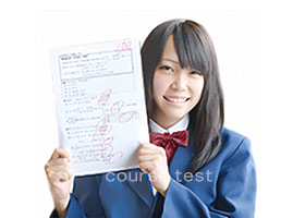 １００点のテストを掲げる高校生の画像。